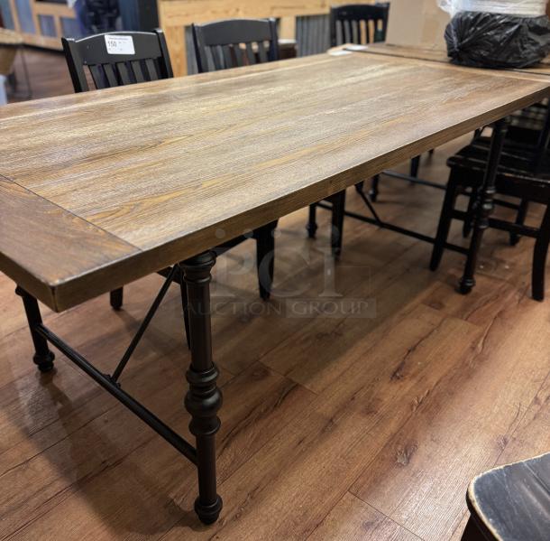 Wooden dining table with a distressed finish, black metal legs, and a rustic style. Visible pricing tag on chair back.