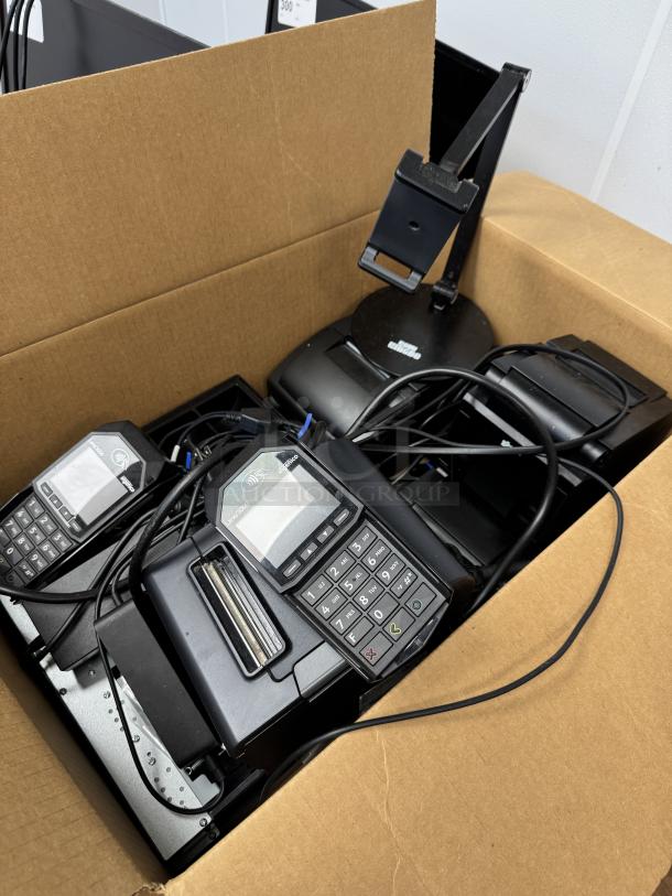 Box with assorted cables, card terminals, and a printer in used condition. Includes cash drawer and mount stand parts.