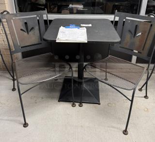 Metal table with two matching chairs, black finish, lattice seat design, decorative backrest cutout, in fair condition.