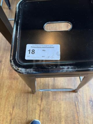 Black metal stool with a square seat, featuring visible wear on edges. Auction tag shows lot number 18 and bid quantity x5.