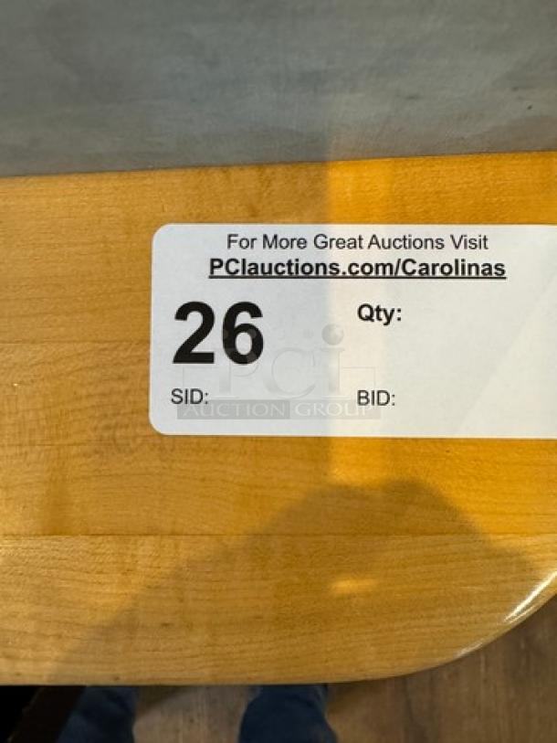 Wooden dining table with a light finish, corner detail shown. Auction label with "PCauctions.com/Carolinas" and lot number 26.