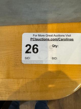 Wooden dining table with a light finish, corner detail shown. Auction label with "PCauctions.com/Carolinas" and lot number 26.