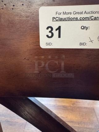 Close-up of a wooden dining chair with a rich brown finish. Visible auction label reads "31, Qty: 6, Bid: x," indicating set for auction.