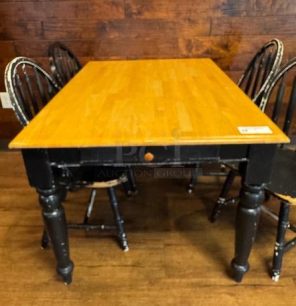 Wooden dining table with light wood top and dark legs, showing wear. Accompanied by four matching chairs.