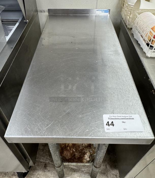 Stainless equipment stand, lightly scratched, with galvanized lower shelf. Auction tag 44 visible. Suitable for kitchen use.