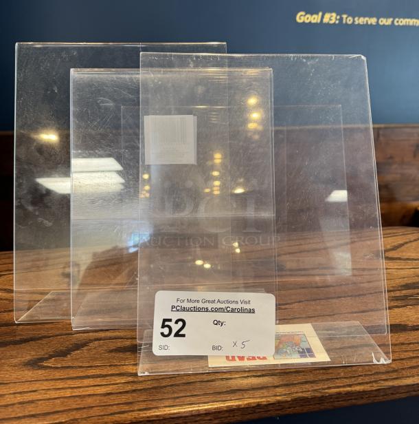 Clear acrylic advertisement holder set, five pieces, with visible scuffing. Auction label reading "52" for tracking.