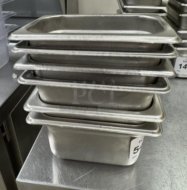 1/6 x 4 stainless steel pans with lids, used condition, stacked, with auction tags indicating 6 available for bidding.