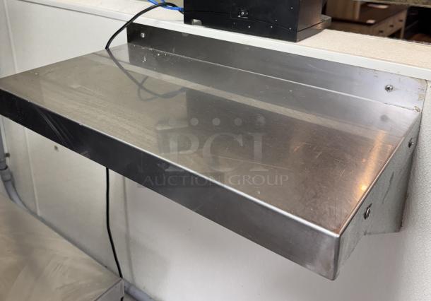 Stainless steel shelf, 48x10x12, mounted on wall. Smooth surface with minor wear. Ideal for kitchen or storage use.