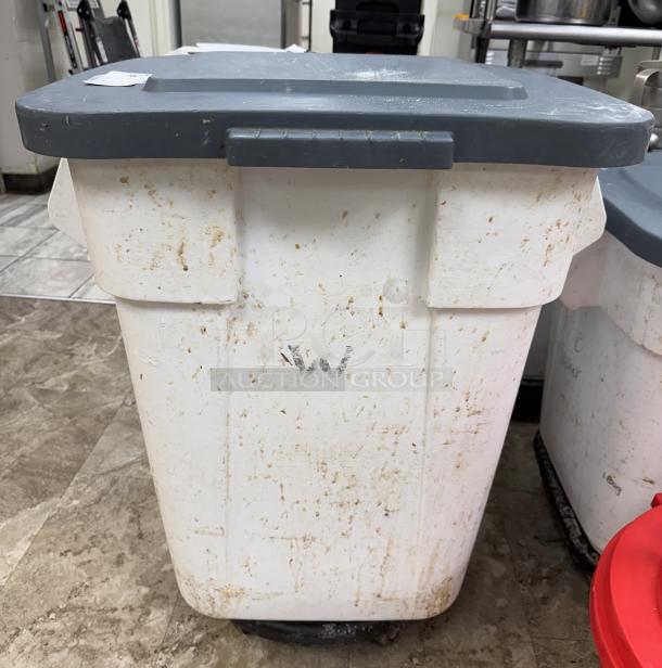 Rubbermaid 28 Gal. dry goods storage container on casters, white, with gray lid. Signs of wear and surface stains visible.