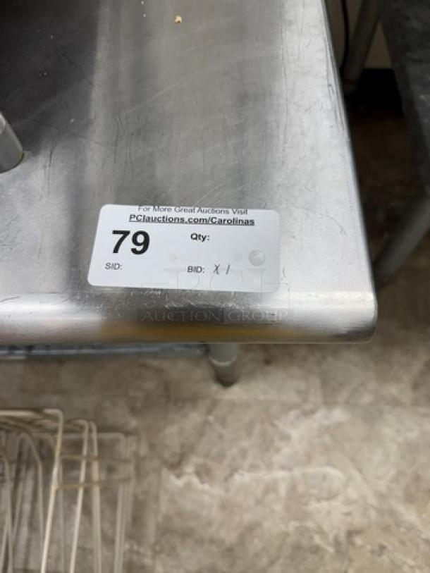 Stainless steel equipment stand with undershelf, labeled "79", auction detail tag, sturdy condition, ideal for kitchen use.