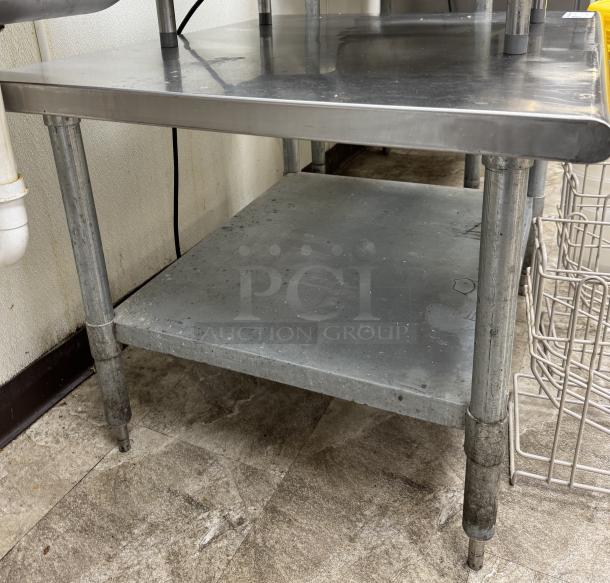 Stainless equipment stand with undershelf, sturdy construction, minor surface wear, ideal for kitchen or industrial use.