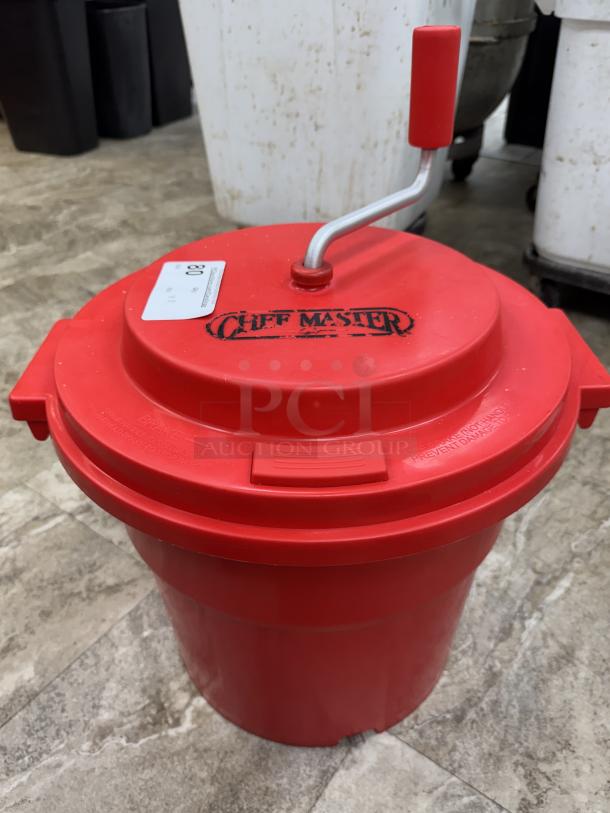 Red Chefmaster Spinner/Strainer with hand crank, branded lid, and brake feature. Good condition. Ideal for kitchen use.