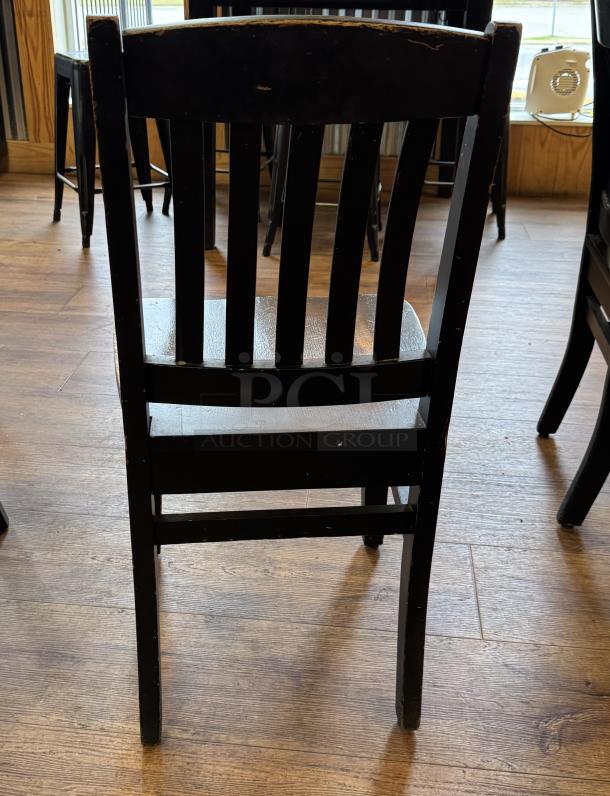Set of 4 black dining chairs with slatted backs, wood construction, minor wear, sturdy condition. Ideal for dining spaces.