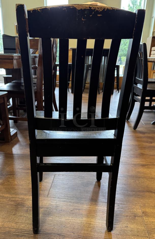 Four black dining chairs, wooden, with visible wear on backrests and legs. Ideal for restoration or rustic decor.