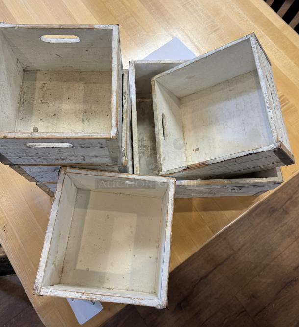 Assorted decorative square wooden boxes, rustic white finish, set of 7, with handles, visible wear, ideal for display/storage.