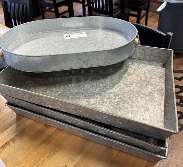 Oval and rectangular tin trays, decorative, galvanized finish, good condition, numbered tag visible, set of four.