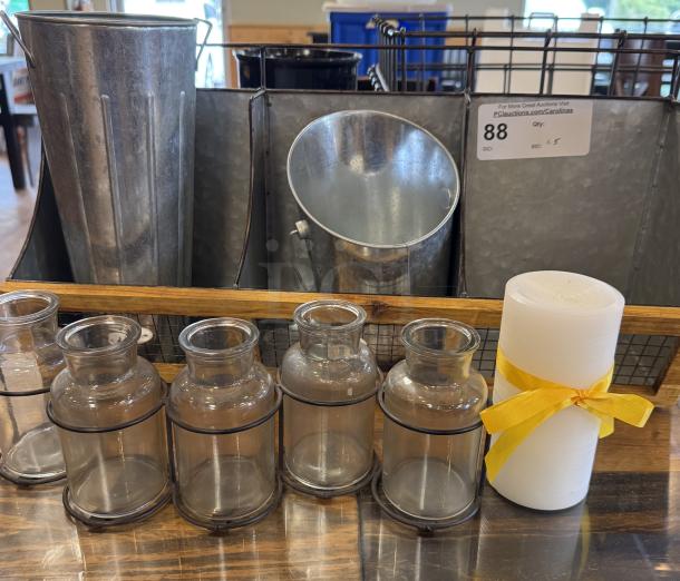 Assorted table displays and glass vases with metal accents. Includes decorative vases and a candle with a yellow ribbon.