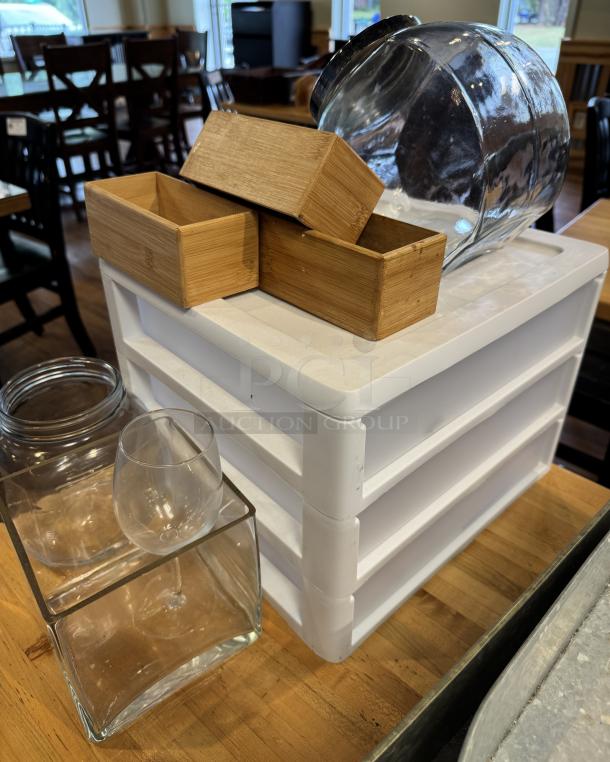 Assorted storage items, including clear glass containers, wooden boxes, and a white plastic drawer set. Used condition.