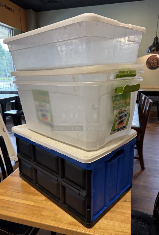 Assorted plastic totes, four pieces, stacked. Includes white and blue totes, some with locking lids. Moderate use condition.