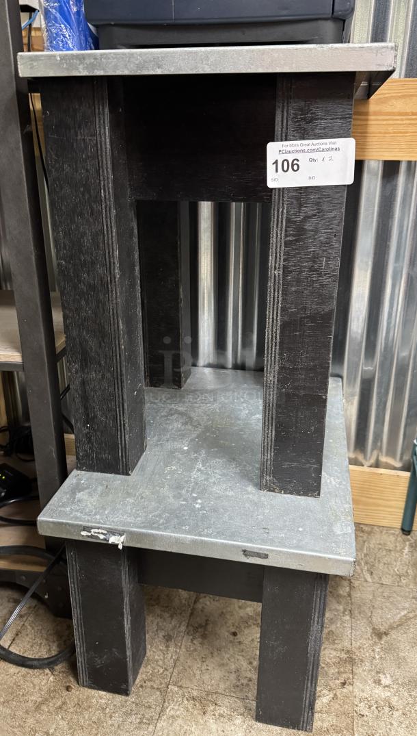 Two metal-top wooden tables stacked; sizes 17x14x23 and 17x18x23 inches. Visible wear. Auction tag "106."