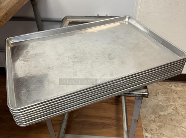 Stack of 10 full-size aluminum sheet pans, gently used, visible minor surface wear, ideal for commercial baking.