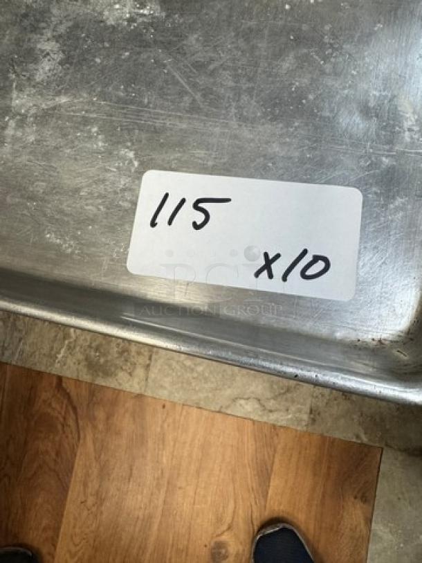 10 full-size sheet pans, used condition, metal surface with wear. Label reads "115 x 10" indicating quantity.