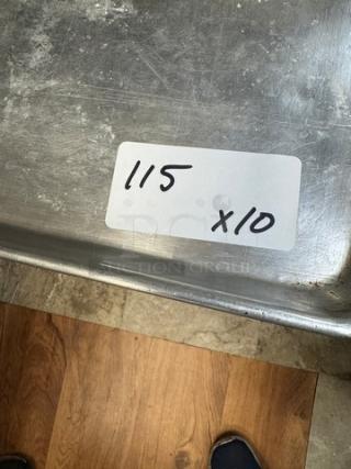10 full-size sheet pans, used condition, metal surface with wear. Label reads "115 x 10" indicating quantity.