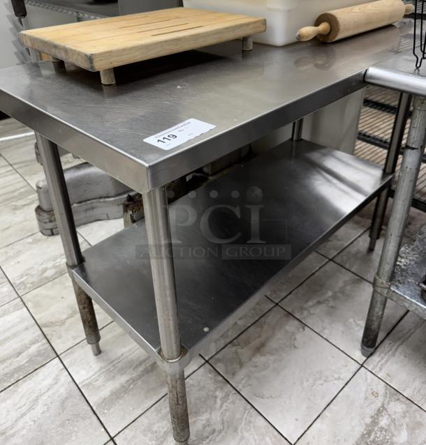 Stainless steel table with undershelf, good condition, label showing item number 119, sturdy and spacious, ideal for kitchen use.