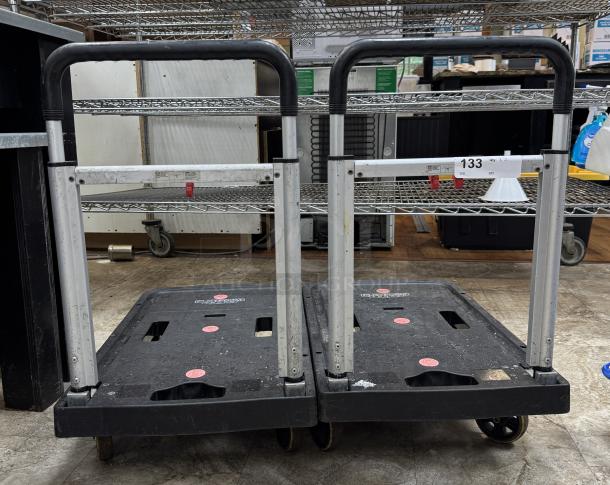 Two rolling folding platform trucks with black handles and platforms, displaying model and serial numbers.  Used condition.