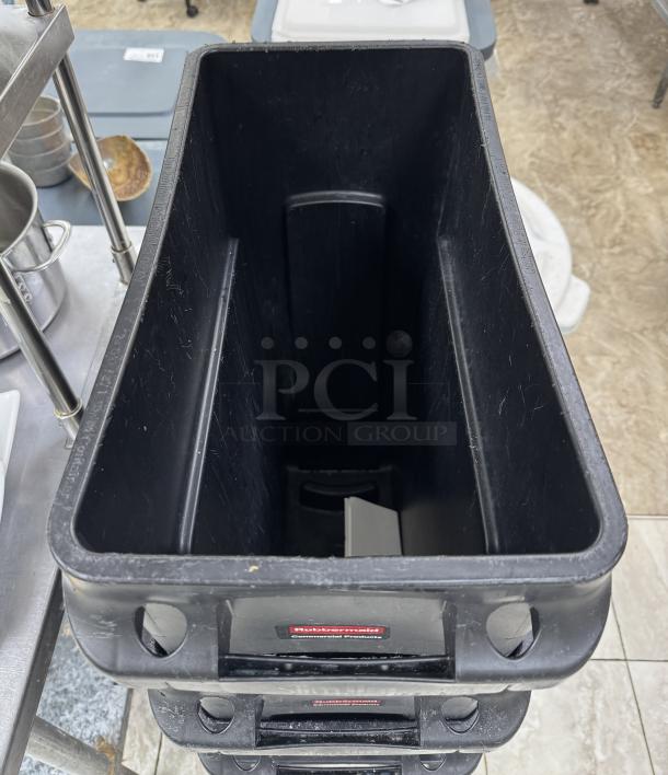 Rubbermaid 23 Gal. Containers, set of 4, used condition, black plastic, visible signs of wear, with official labels.