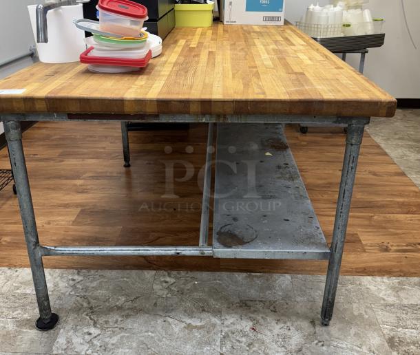Large butcher block top table with galvanized legs, features sturdy lower shelf, used condition, ideal for kitchen or workshop use.