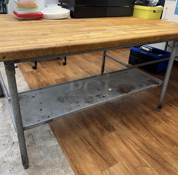 Large butcher block top table with galvanized legs and lower shelf, showing signs of wear. Ideal for kitchen or workspace use.