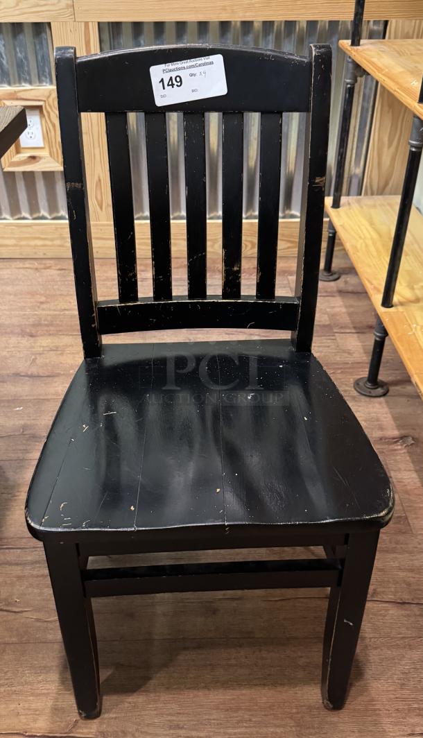 Black dining room chair with vertical slat backrest, minor wear marks. Auction tag reads "149, Qty: 4".