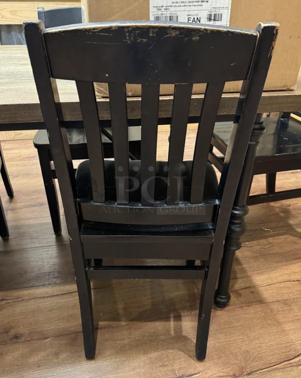 Set of 4 black dining room chairs with slatted backs, showing visible wear on edges; sturdy wooden construction.