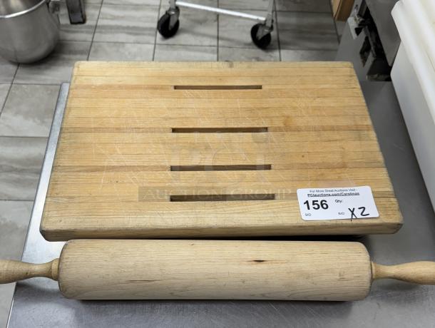 Wooden cutting board with slotted design and 24" rolling pin. Both show moderate wear. Auction tag reads "156 X2."