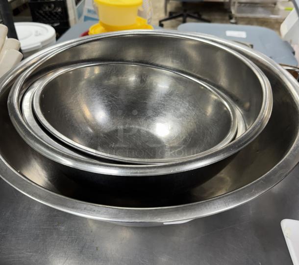 Stainless steel mixing bowls set, 4 pieces, nested, gently used condition, ideal for kitchen tasks.