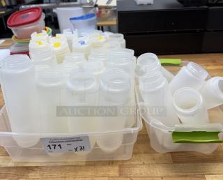 Assorted plastic condiment dispensers, 31 total, in clear bins with green handles. Some lids are colored. Used condition.
