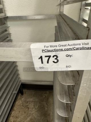 Metal rolling sheet pan rack with multiple shelves, silver finish, auction tag numbered 173 visible. Suitable for bakery use.