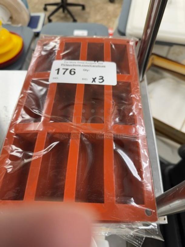 Red silicone baking molds, 3-pack, new in packaging. Rectangular shape with six cavities each. Auction label reads "176 Qty x3".