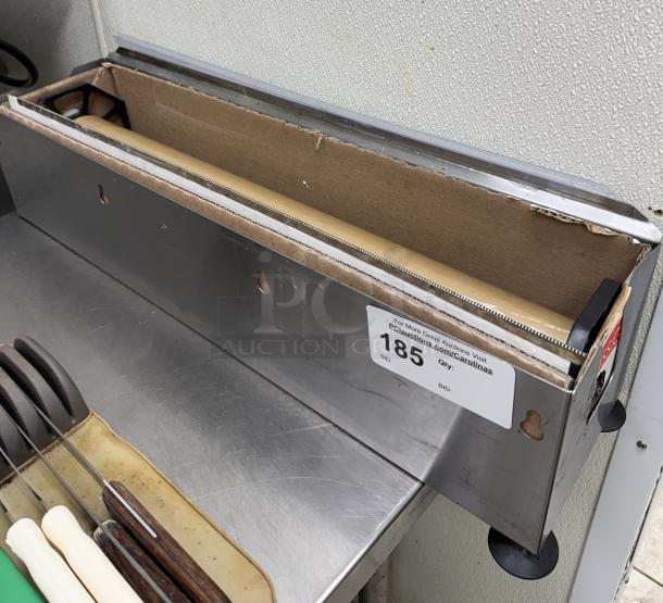 Metal plastic wrap holder/cutter with a serrated edge, wall-mountable design, and auction label marked "185."