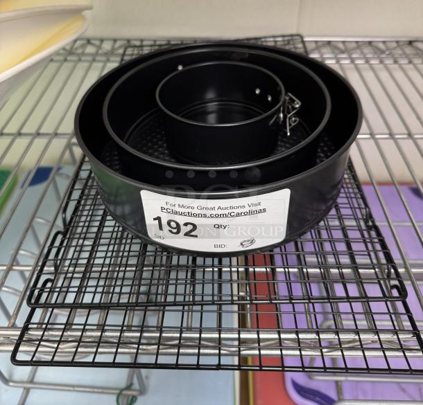 Expandable cake pans set with 4", 7", 8.5" sizes and cooling racks. Includes auction label with item number 192.