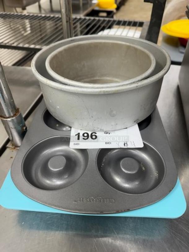 Stack of mini bundt and cake pans, featuring silicone and metal materials. Includes a Nordic Ware mini bundt pan. Item tag 196 visible.
