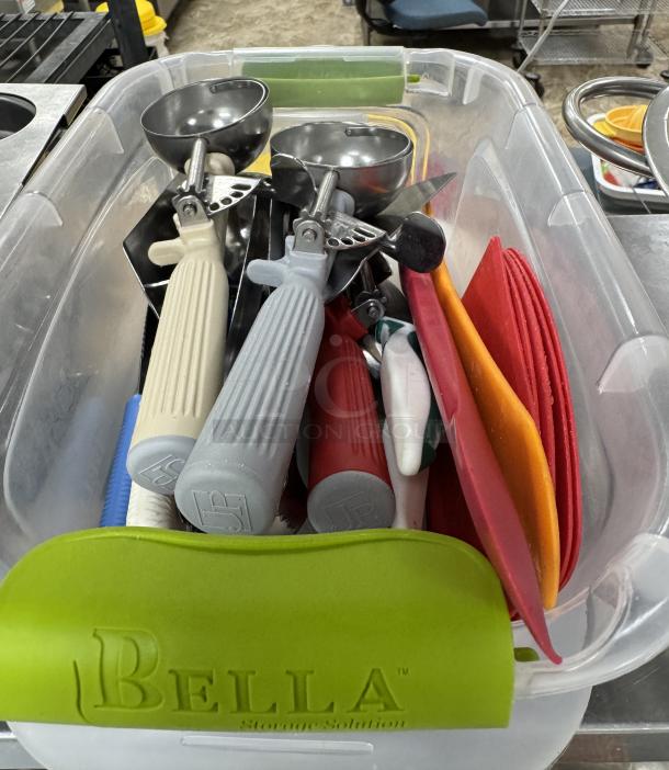 Assorted baking utensils in a clear Bella container; includes scoops, spatulas, cutters. Used, good condition.