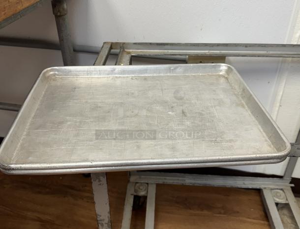Half size sheet pan with visible wear, made of aluminum. Measures approximately 10 inches wide. Auction lot includes 10 pans.