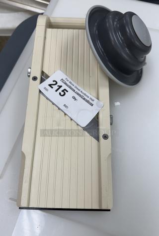 Cream-colored kitchen slicer mandolin with blade, in good condition. Auction tag marked “215,” indicating lot number.