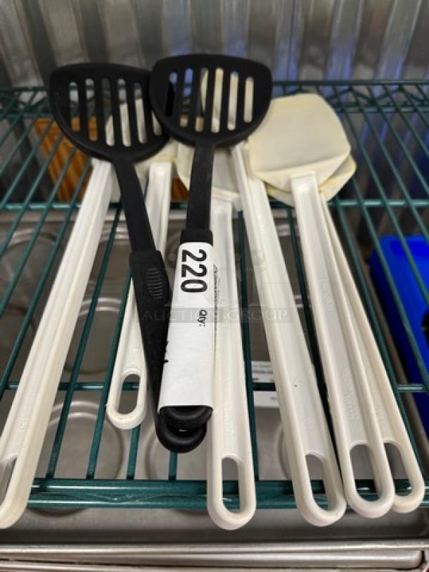 Set of 8 black and white mixing spoons and spatulas, plastic handles, used condition, each tagged as item 220.