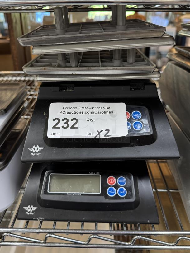 Myweigh Digital Scales, model KB7000, dual unit auction item. Features keypad controls and display screen. Good condition.