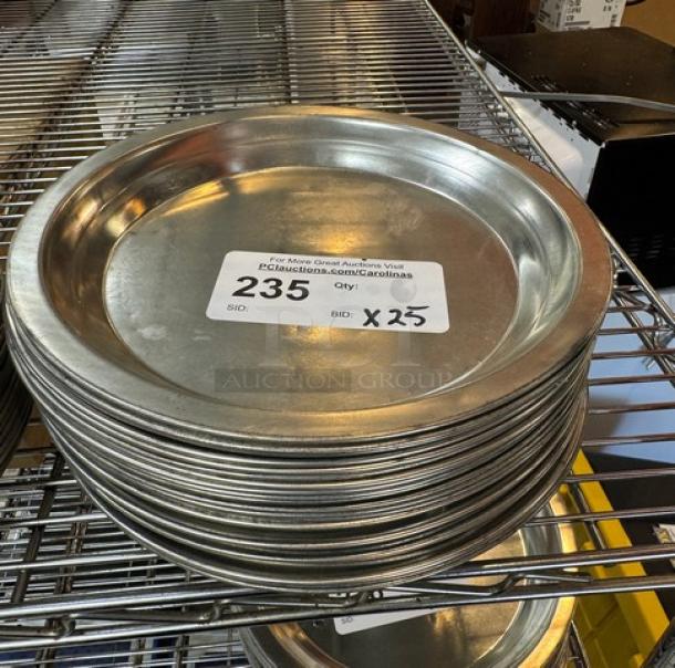 Stack of 25 metal pie pans on a wire shelf, each marked with auction label indicating "235, Qty: 25."