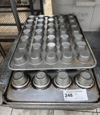 Eight steel cupcake pans, stacked, showing slight wear. Each pan holds 48 cupcakes. Label indicates lot number 248.