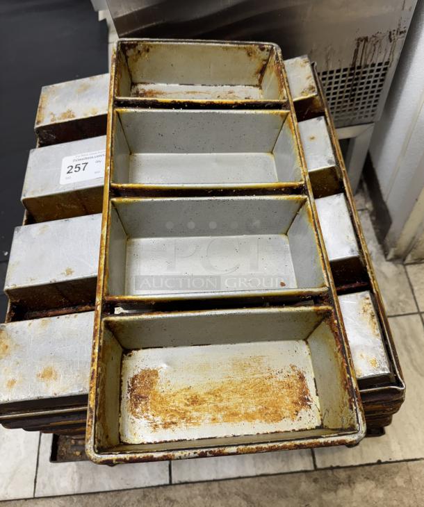 Stack of used bread pans, visible rust and wear, label marked "257". Set of 12 pans, ideal for bulk baking.